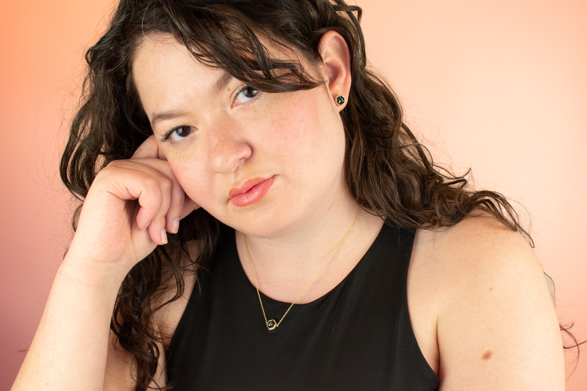 model looking into camera wearing matching geometric necklace and stud earrings in black terrazzo