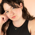 brunette mold looking into camera wearing matching gold hexagon earrings and necklace in black stone terrazzo