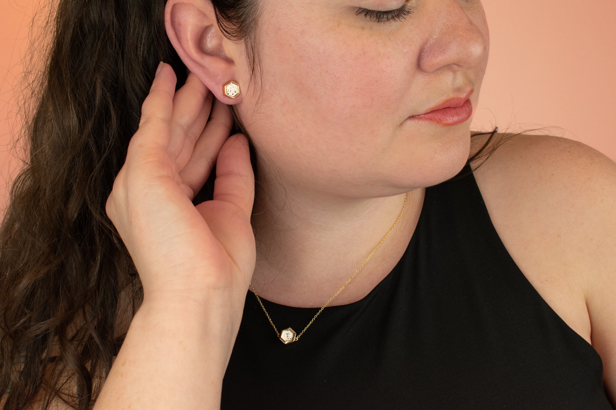 model wearing matching gold hexagon necklace and earrings in speckled terrazzo stone 