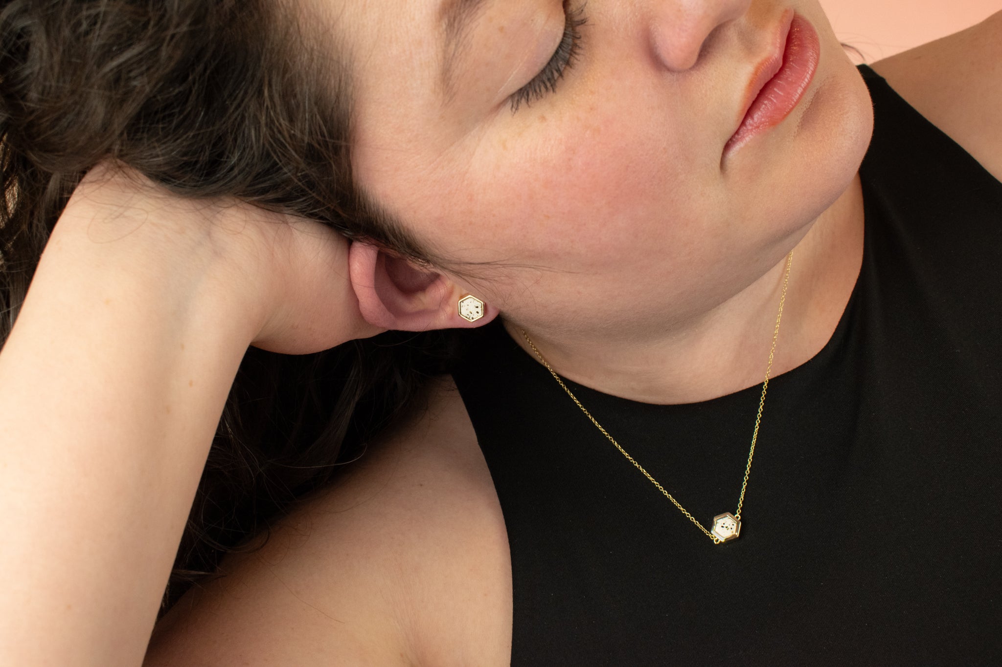 brunette model wearing matching gold contemporary hexagon jewelry with speckled stones