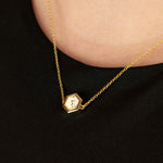 close up of gold cable chain choker in hexagon shape with white clay background speckled with flecks of black and brown