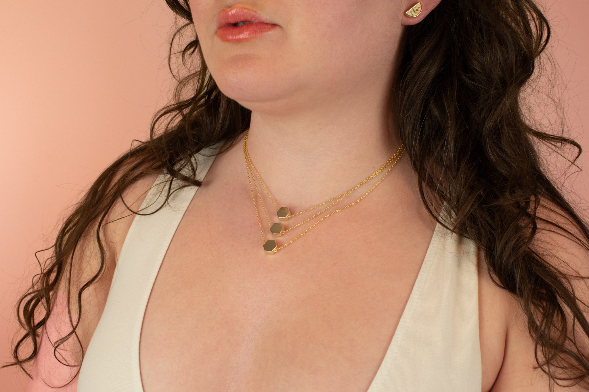 model wearing three contemporary geometric necklaces facing backwards to display gold plating