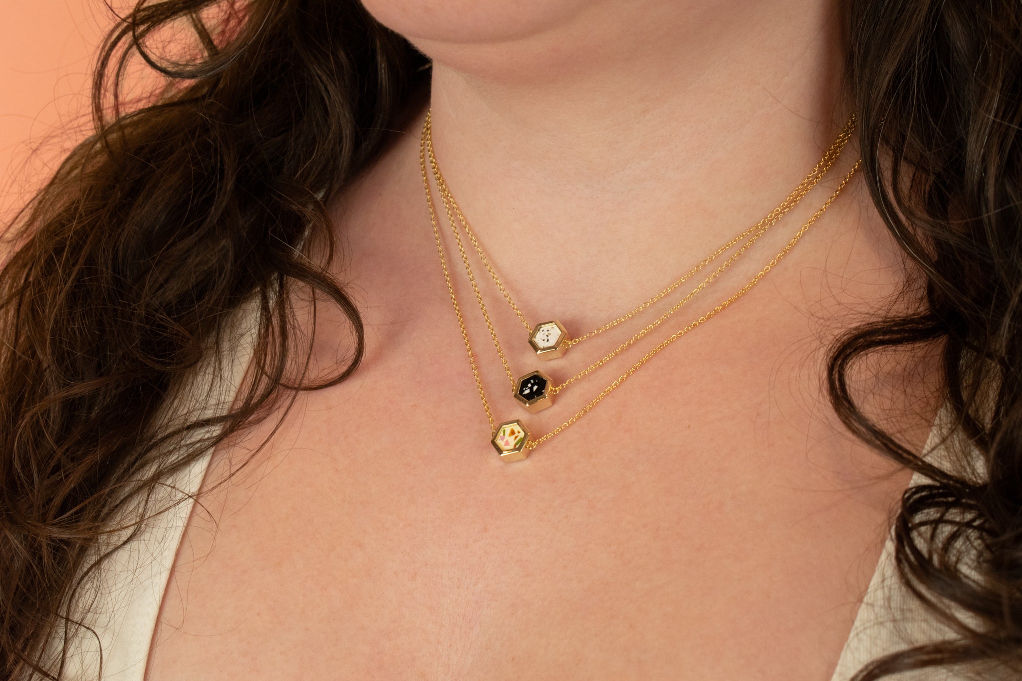 close up shot of model wearing various colorways of gold style terrazzo necklaces