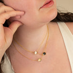 close in of model wearing three hexagon delicate chain necklaces criss crossed at different lengths