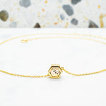 delicate gold chain necklace with speckled granite clay filling laying on a white surface with a terrazzo tile backdrop