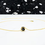 everyday gold and black statement necklace laid out in a circle displayed on white surface with black terrazzo backdrop