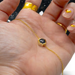 manicured hand in front of black terrazzo background holding gold plated adjustable cable chain necklace in black terazzo