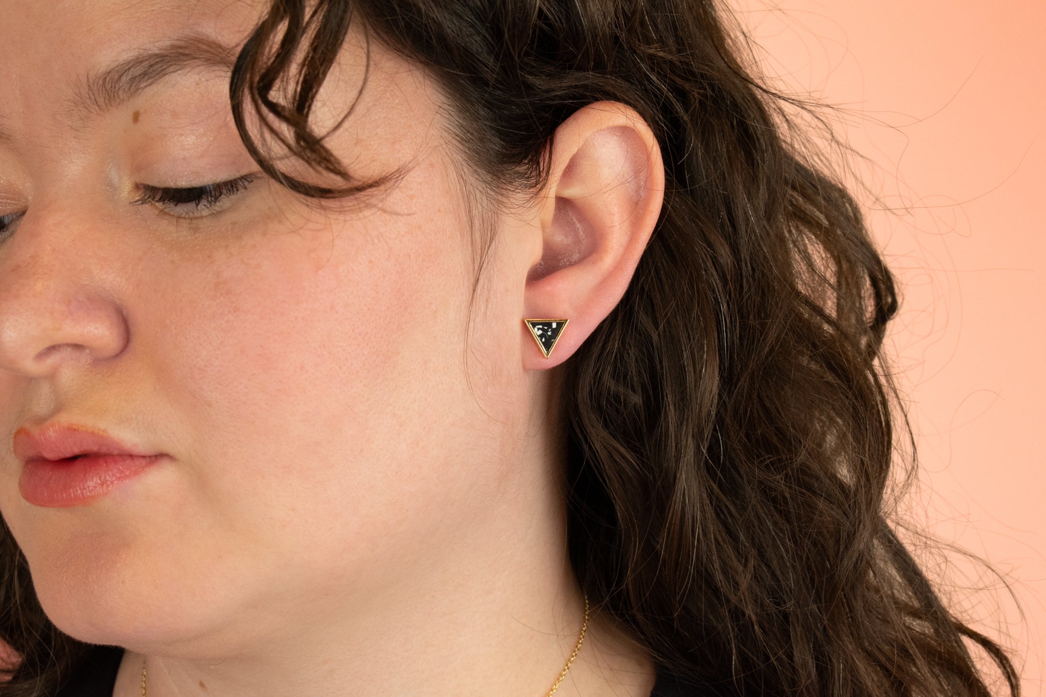 brunette model wearing 14k gold plated black and white statement triangle earrings