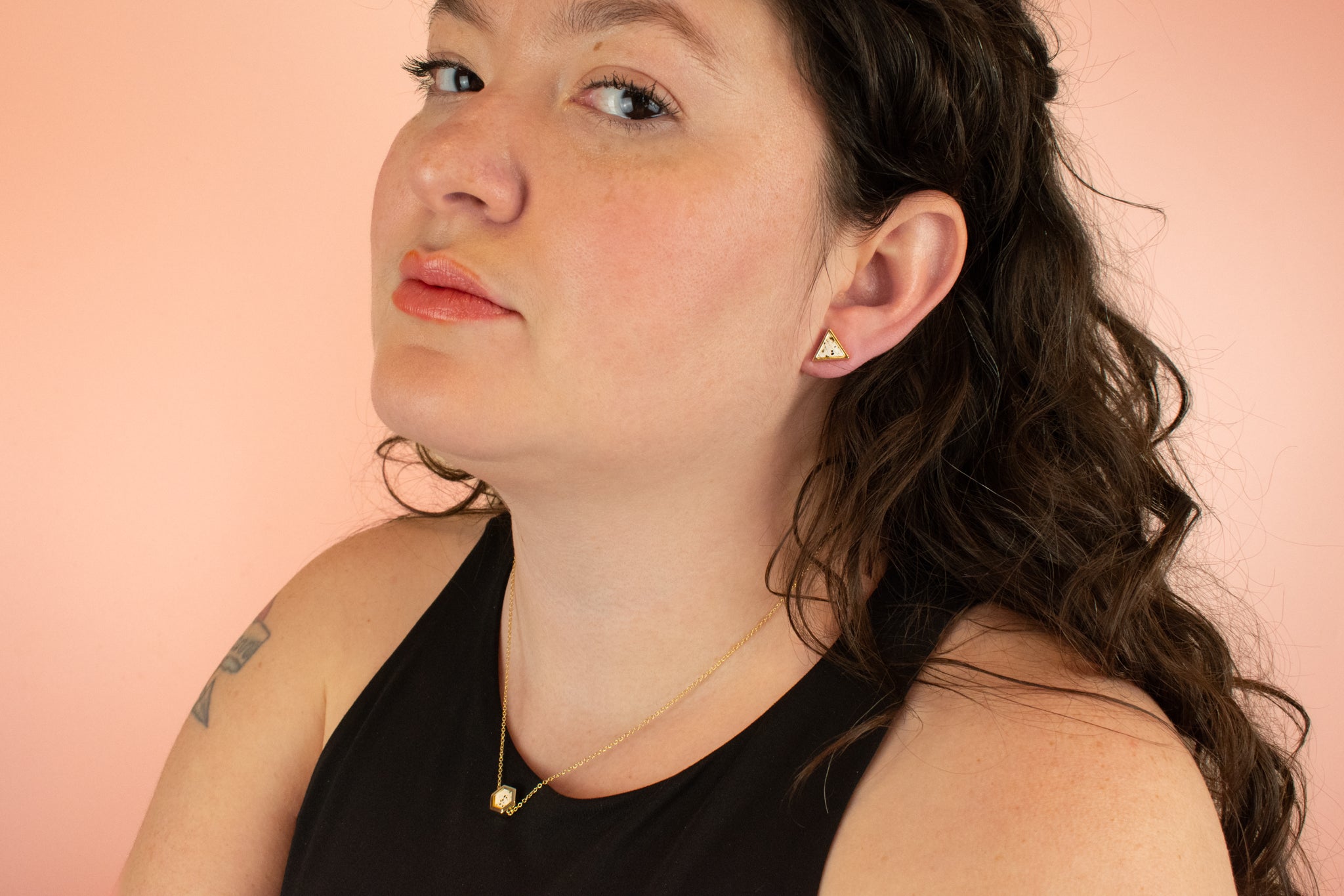 model wearing matching gold geometric earrings and necklace in white terrazzo style