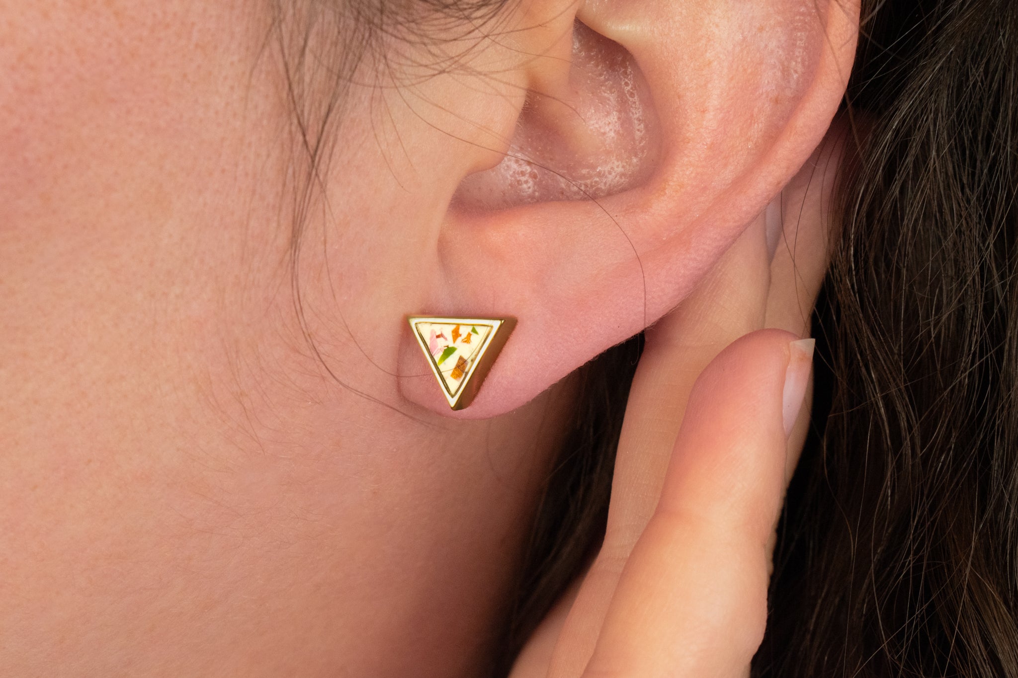 detail shot of unique gold stud earrings in white terrazzo with multicolored angular chips of clay