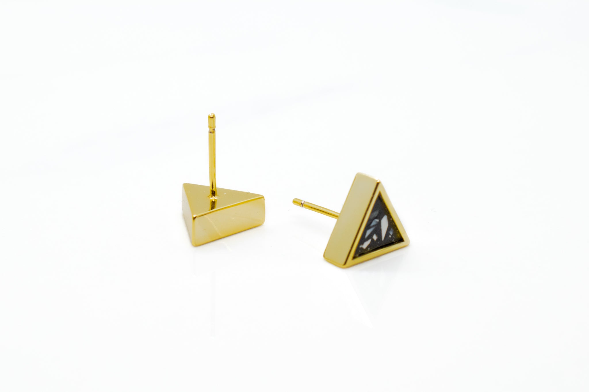 pair of gold geo stud earrings in black stone photographed with one facing post side up and the other camera facing displaying terrazzo design