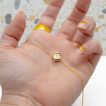 manicured hand in front of a terrazzo backdrop holding modern geometric necklace in dalmatain jasper print