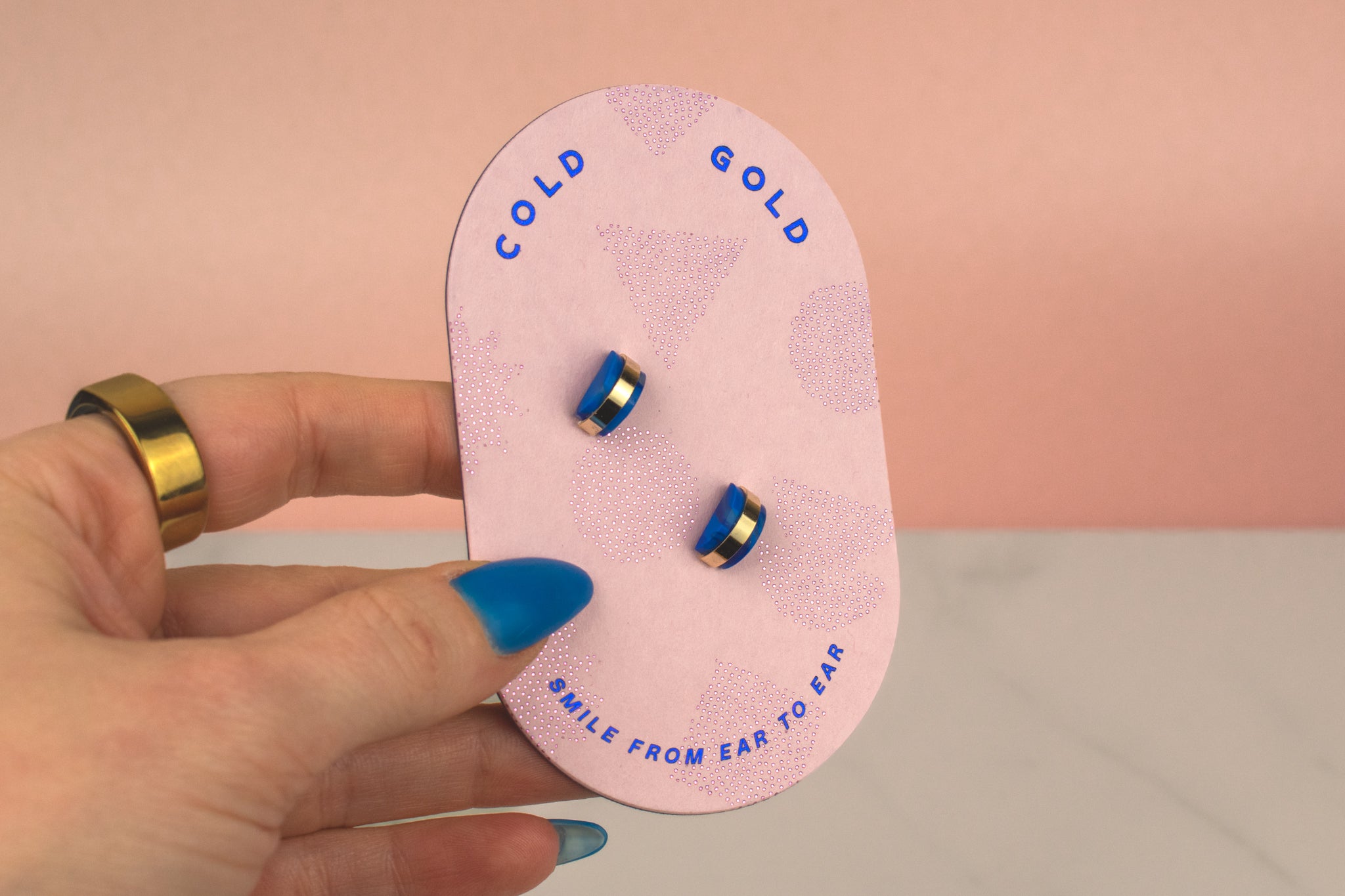hand holding pink card displaying blue sapphire 14k gold earrings