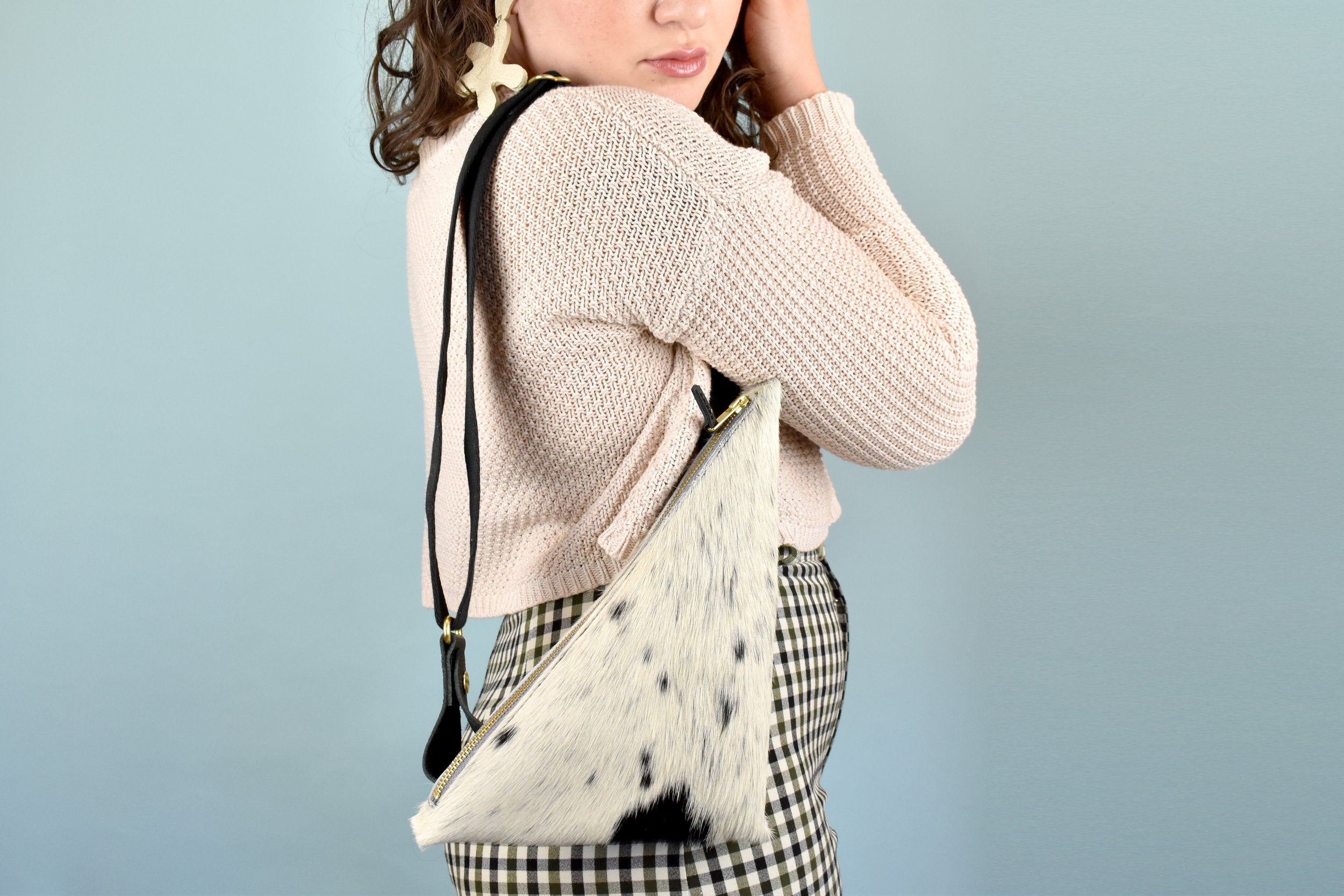 a woman wears a cowprint sling bag for bonnaroo essentials bag small leather sling bag crossbody cowhide leather purse cowprint gift for sister sling purse with inside pocket over her shoulder