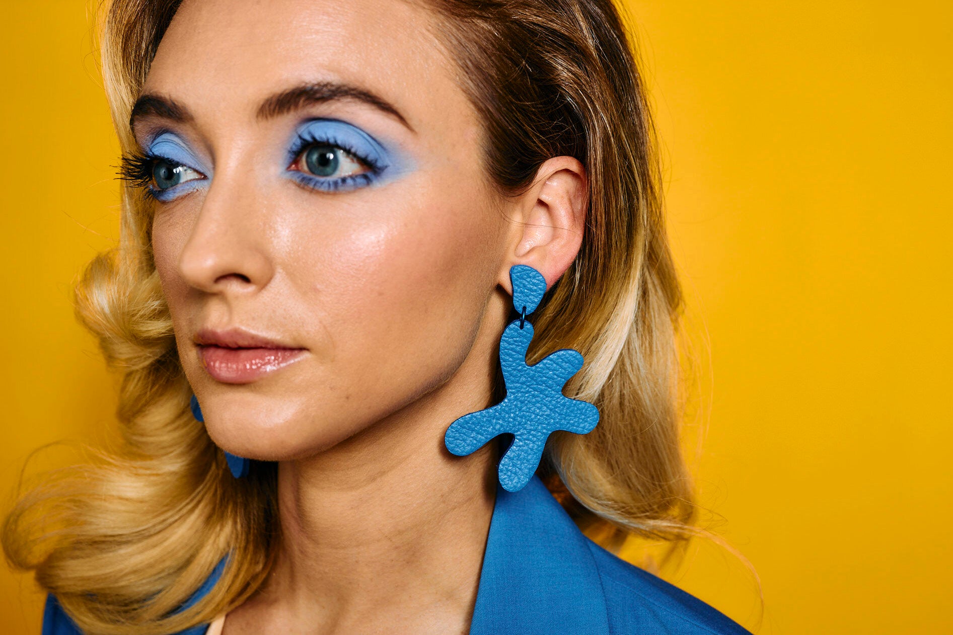 close up of woman wearing oversized leather cutout earrings in matisse blue.