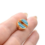 hands holding a pair of  geometric triangle stud earrings in aqua blue birthstone gemstone close up