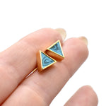hands holding a pair of small geometric triangle earring stud set in gold and aquamarine