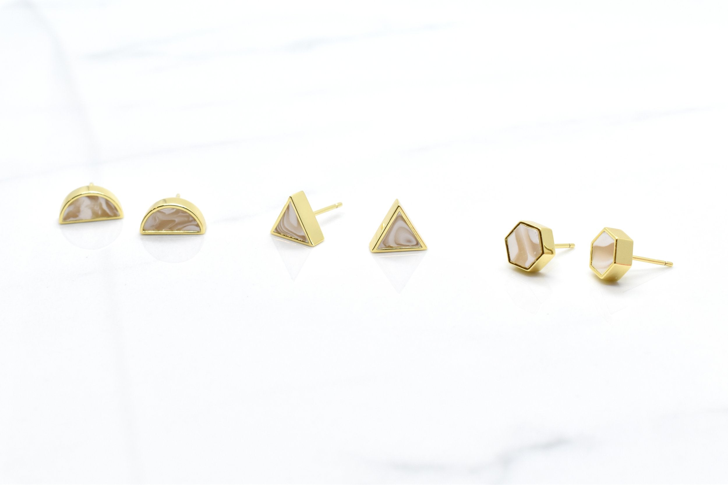 photo showing three pairs of different geometric stud set in 24k gold-plated brass and ivory marbled clay triangle hexagon half moon geometric shapes