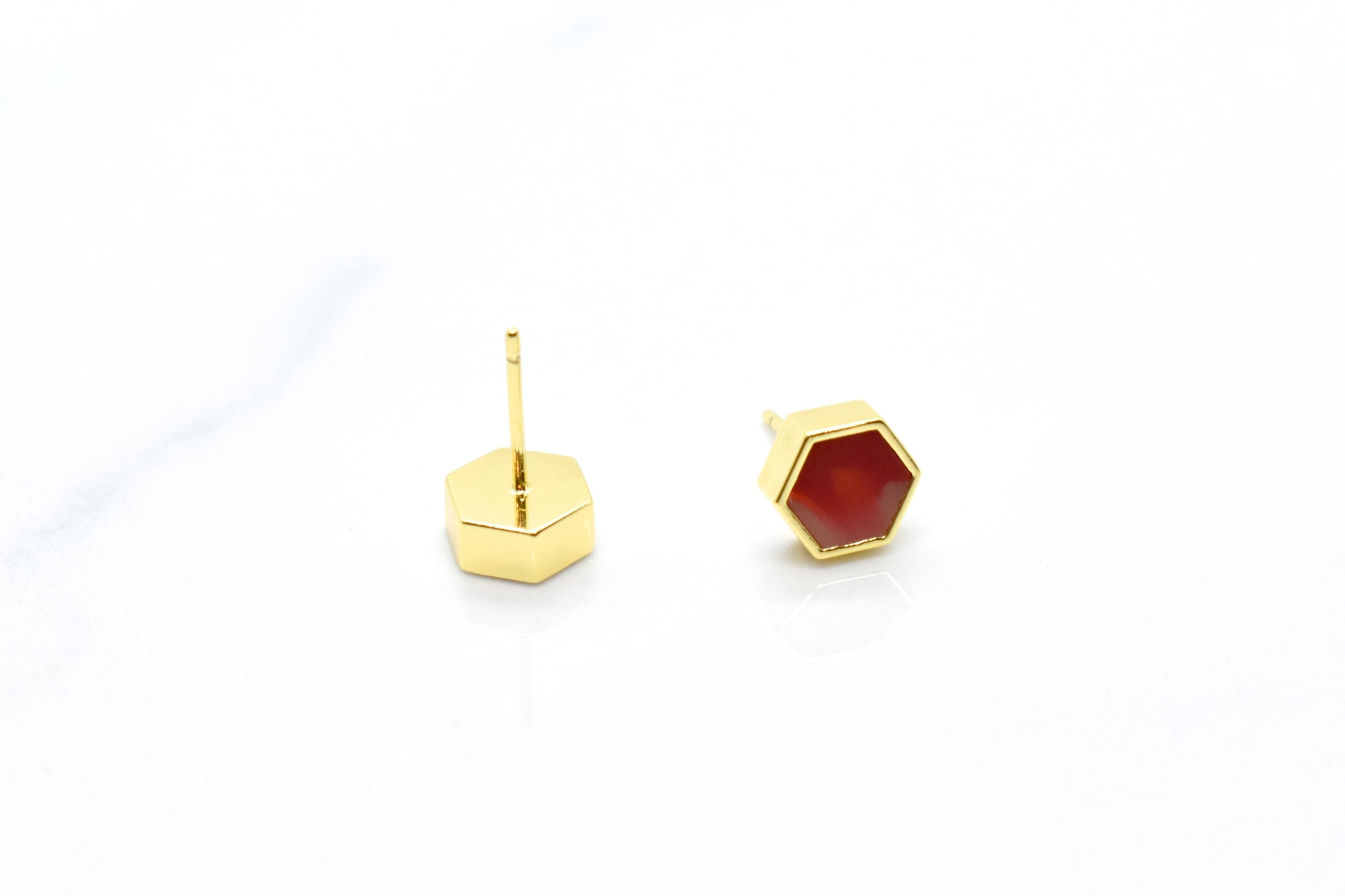 set of ruby stud earrings with gold geometric hexagons showing the back with the surgical steel posts that are hypoallergenic and safe for sensitive ears