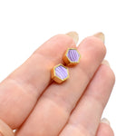 hands holding a pair of lilac hexagon gold stud earrings