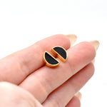 hand holding a pair of half circle stud earrings in gold and black with hypoallergenic 14k gold plated sterling silver posts