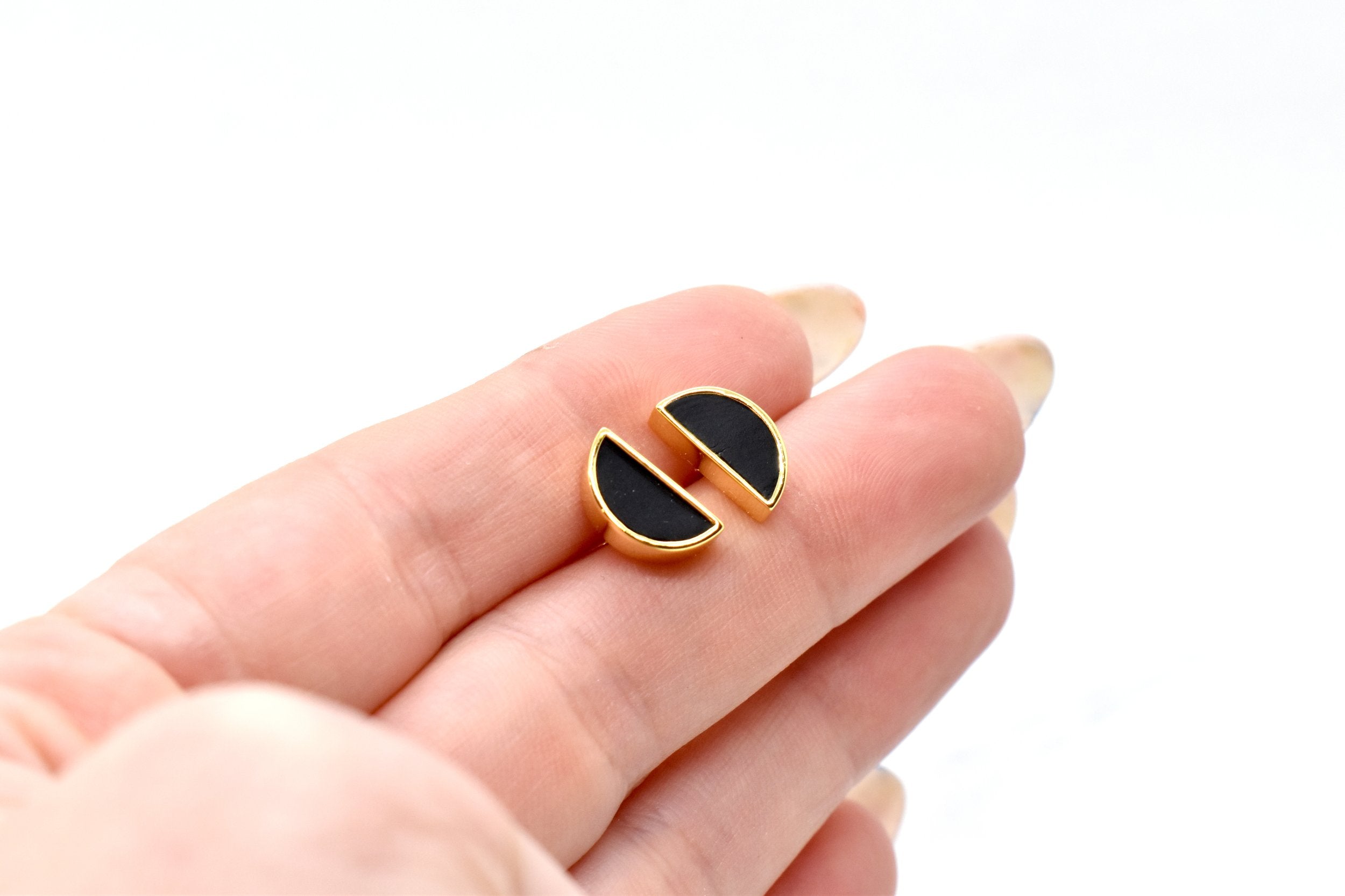 hand holding a pair of half circle stud earrings in gold and black with hypoallergenic 14k gold plated sterling silver posts
