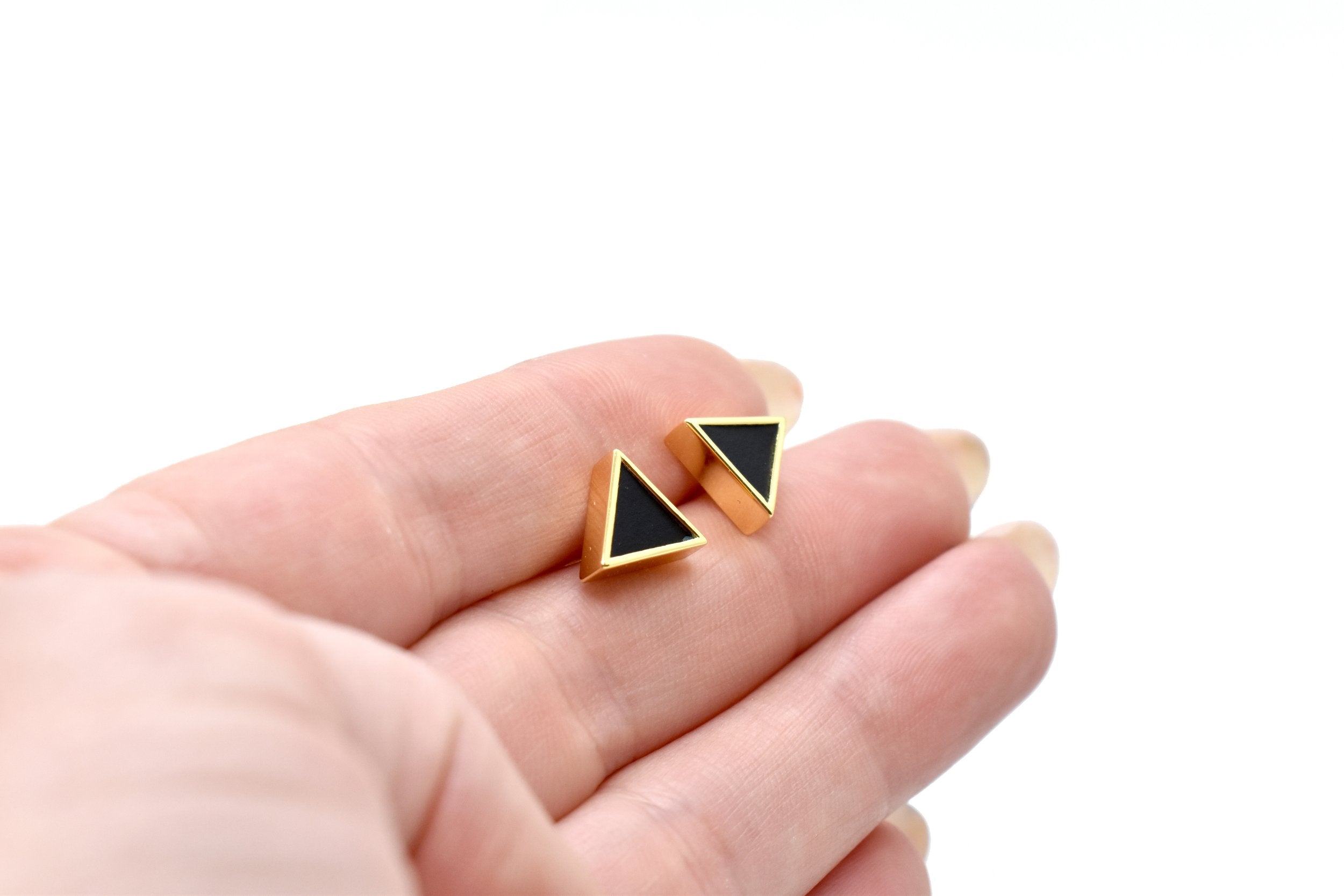 hand holding a pair of gold geometric triangle stud earring set in 14k gold plating good for sensitive ears