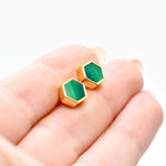 hands holding gold hexagon stud earrings with striped jade gemstone texture and 14k gold hexagon shape against a white background