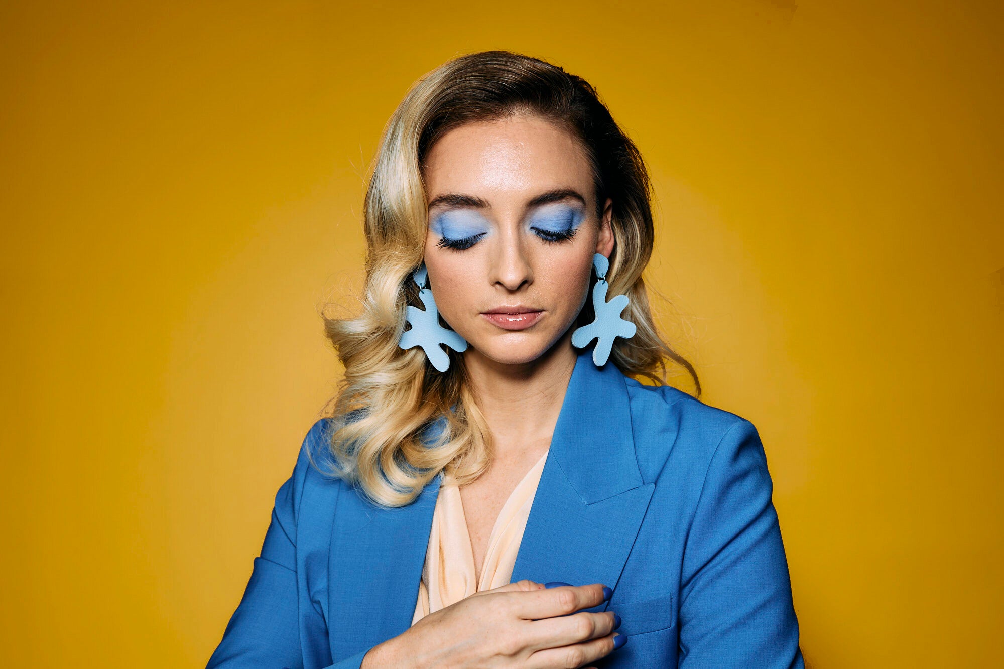 a blonde woman wears starfish shape cutout authentic leather earrings in soft blue.