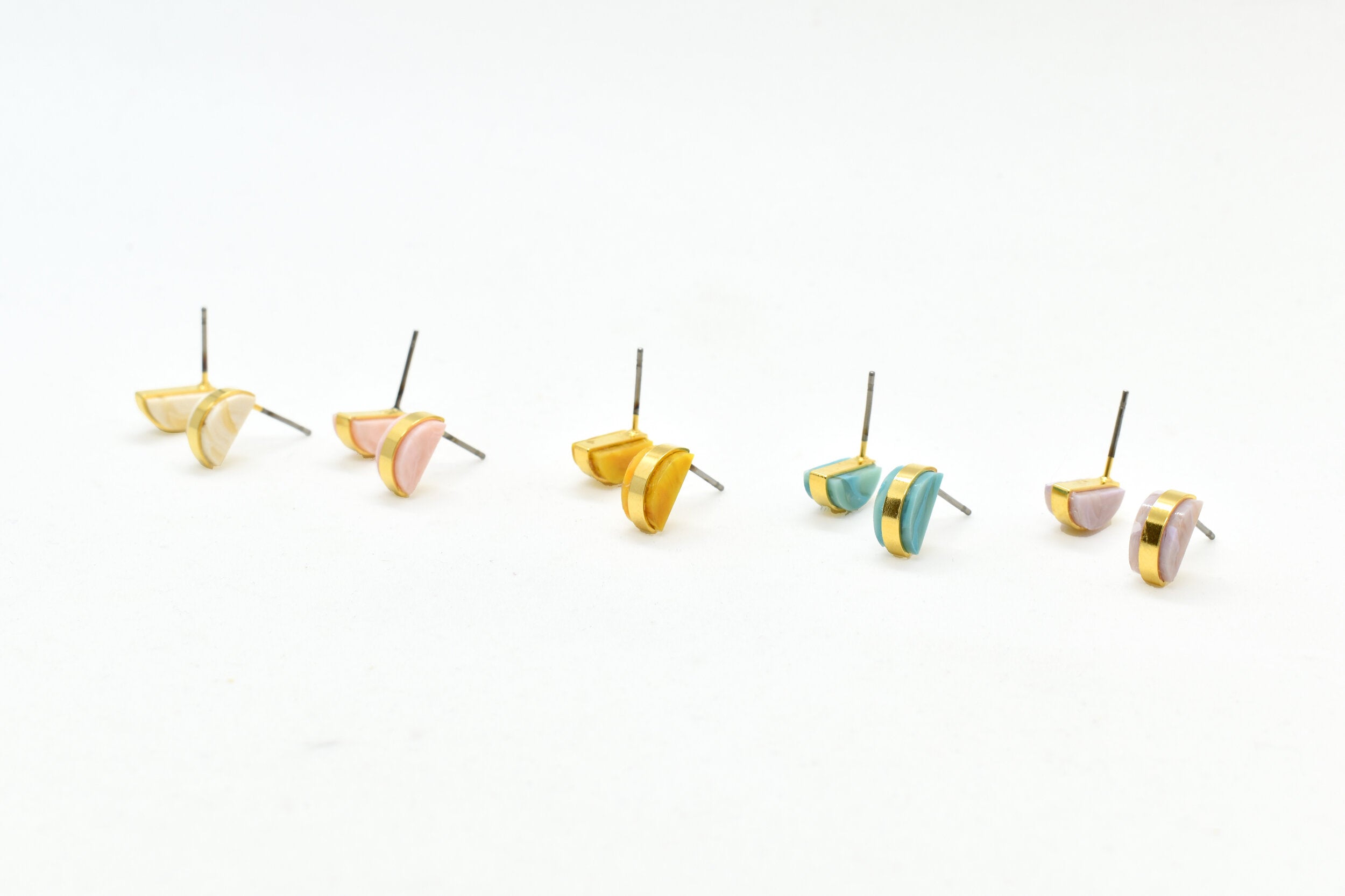 architectural small statement earrings in crystal quartz, rosy pink, golden yellow, aqua blue, and lavender.