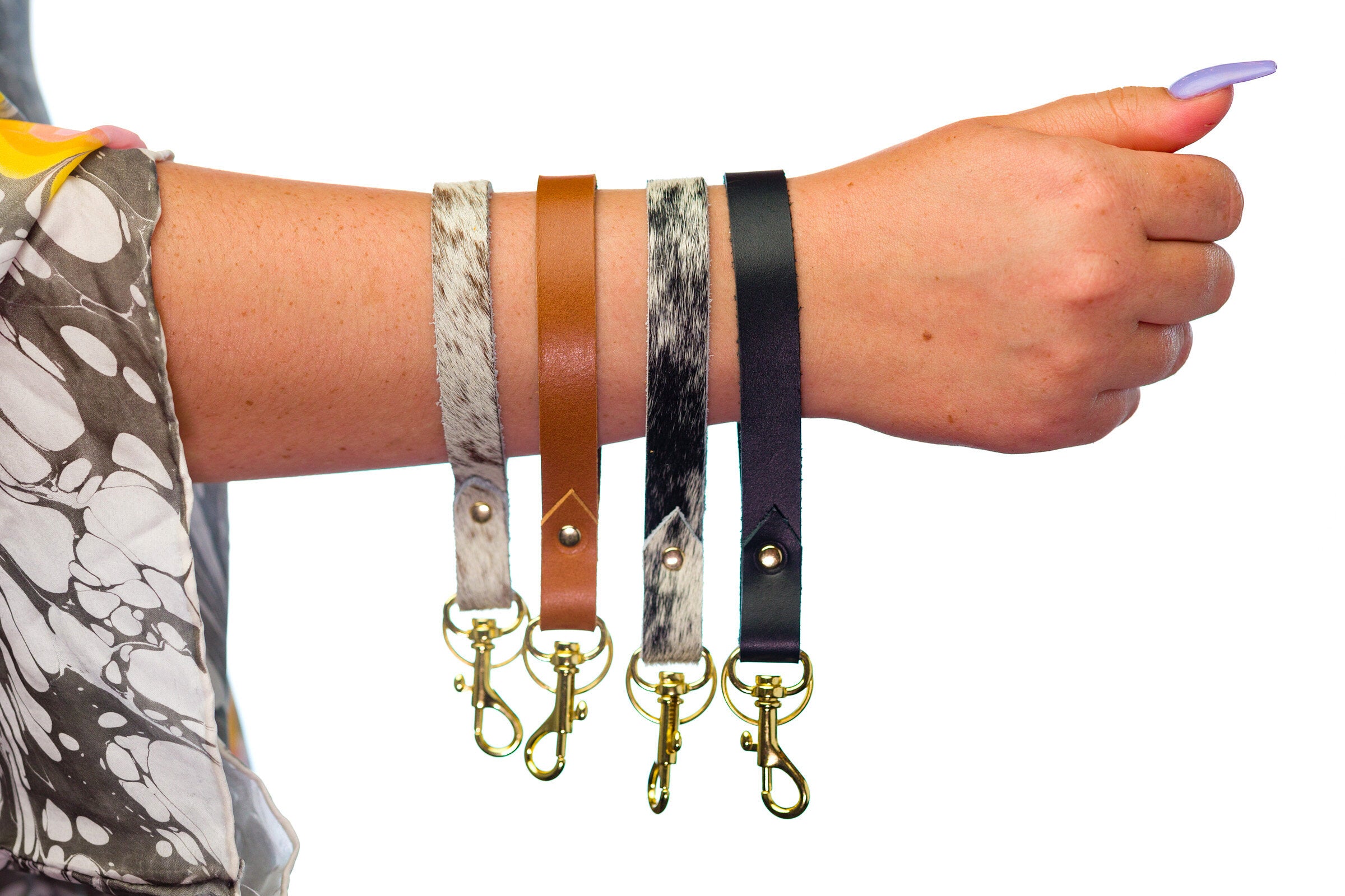 a collection of leather wrist strap loop key chains with gold hardware and varied colors.