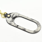 oval shaped leather keychain in black and white hair on hide speckle and black pebbled saddle leather finish.