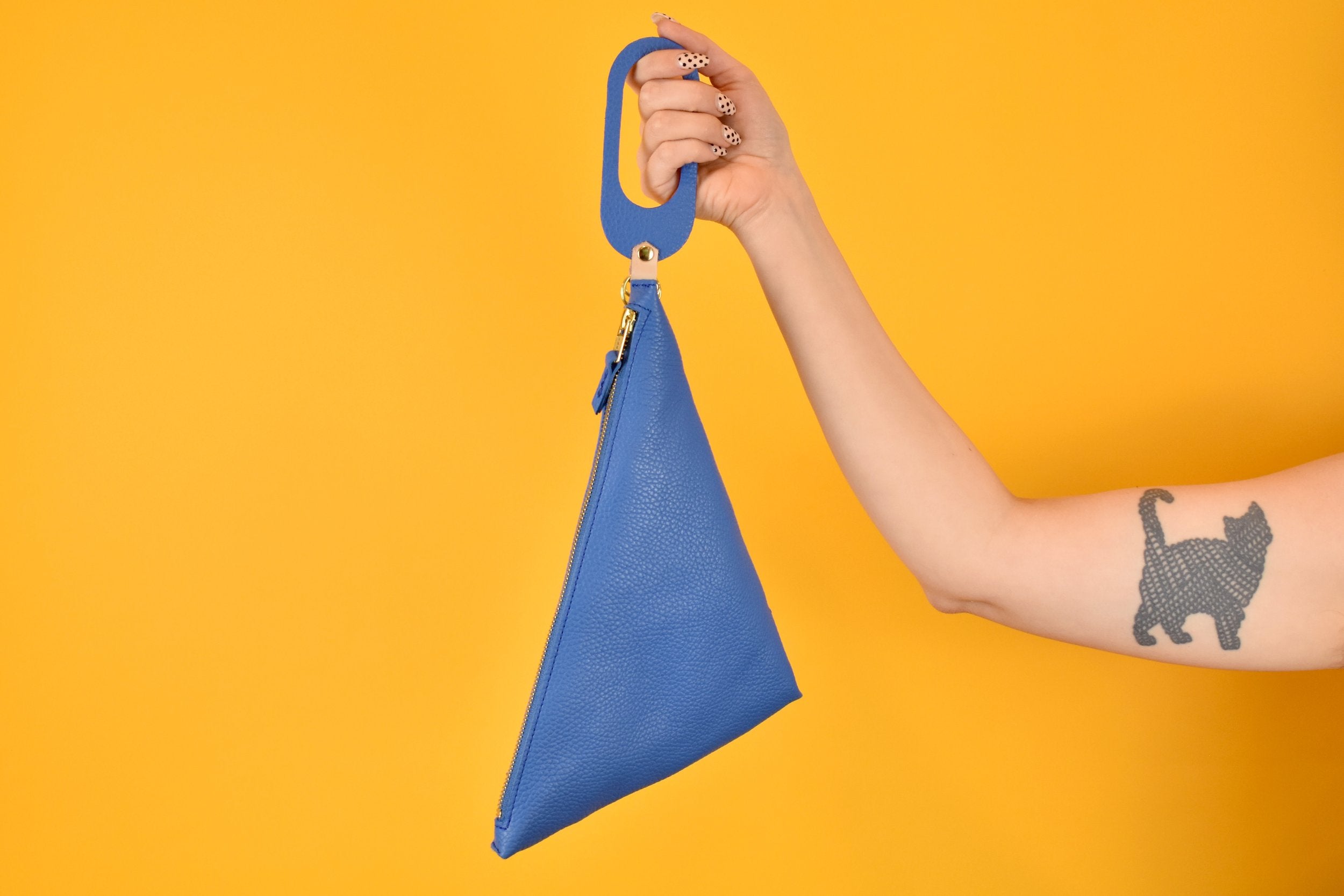 a hand holding a wristlet clutch version of the blue sling bag cute sling in matisse blue perfect for beach trip