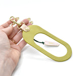 A vegetable tanned rawhide and bright lime green leather finish keychain with gold hardware
