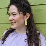 a person wears disco inspired lime green leather statement earrings