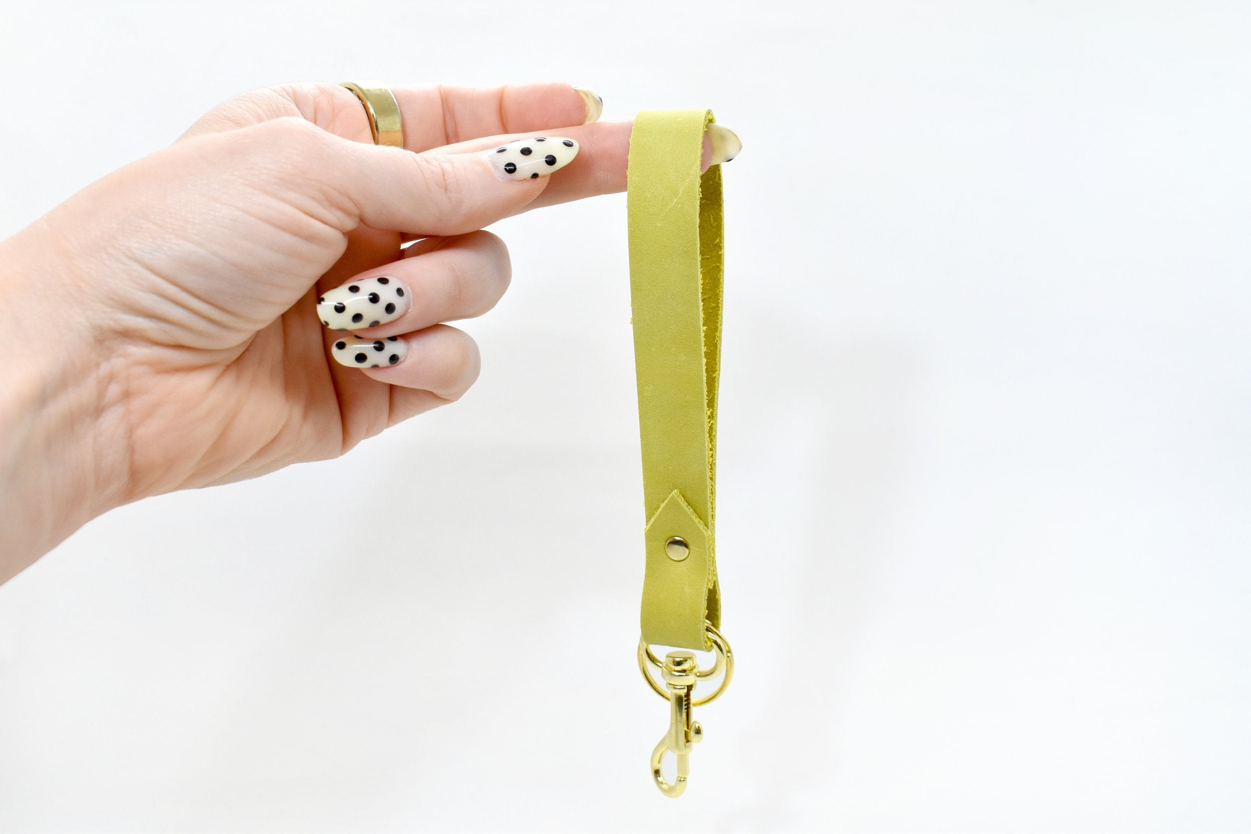 the classic cut leather chartreuse wristlet keychain rests on a finger