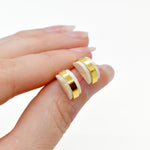 hand holding small architectural stud earring set in clear quartz gold