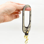 A modern leather keychain with cutout finished with a gold key ring and gold clasp