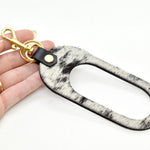 A black and white hair on hide speckle finish keychain with gold hardware.