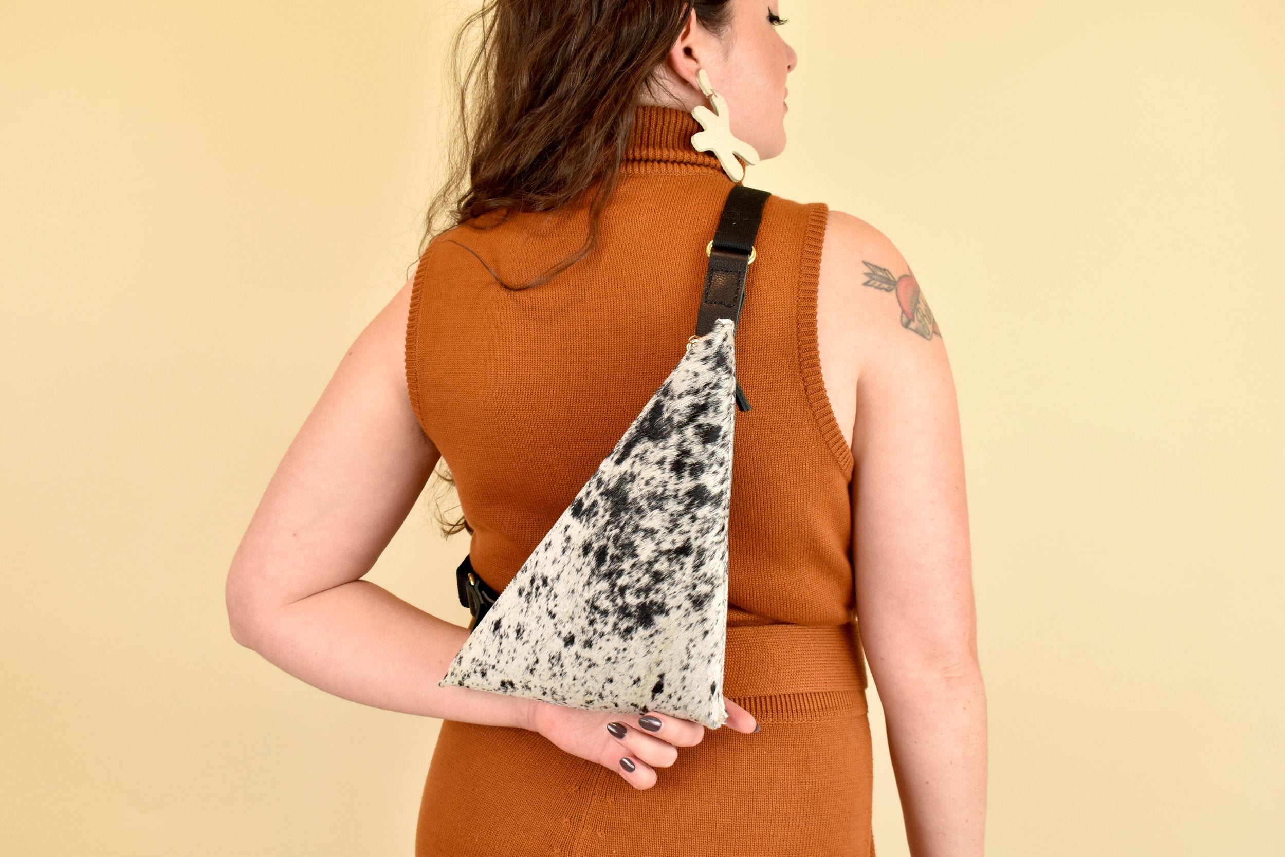 a girl wears a leather sling bag for coachella essentials bag small leather sling bag crossbody cowhide leather purse cowprint gift for bride sling bag with inside pocket on her back