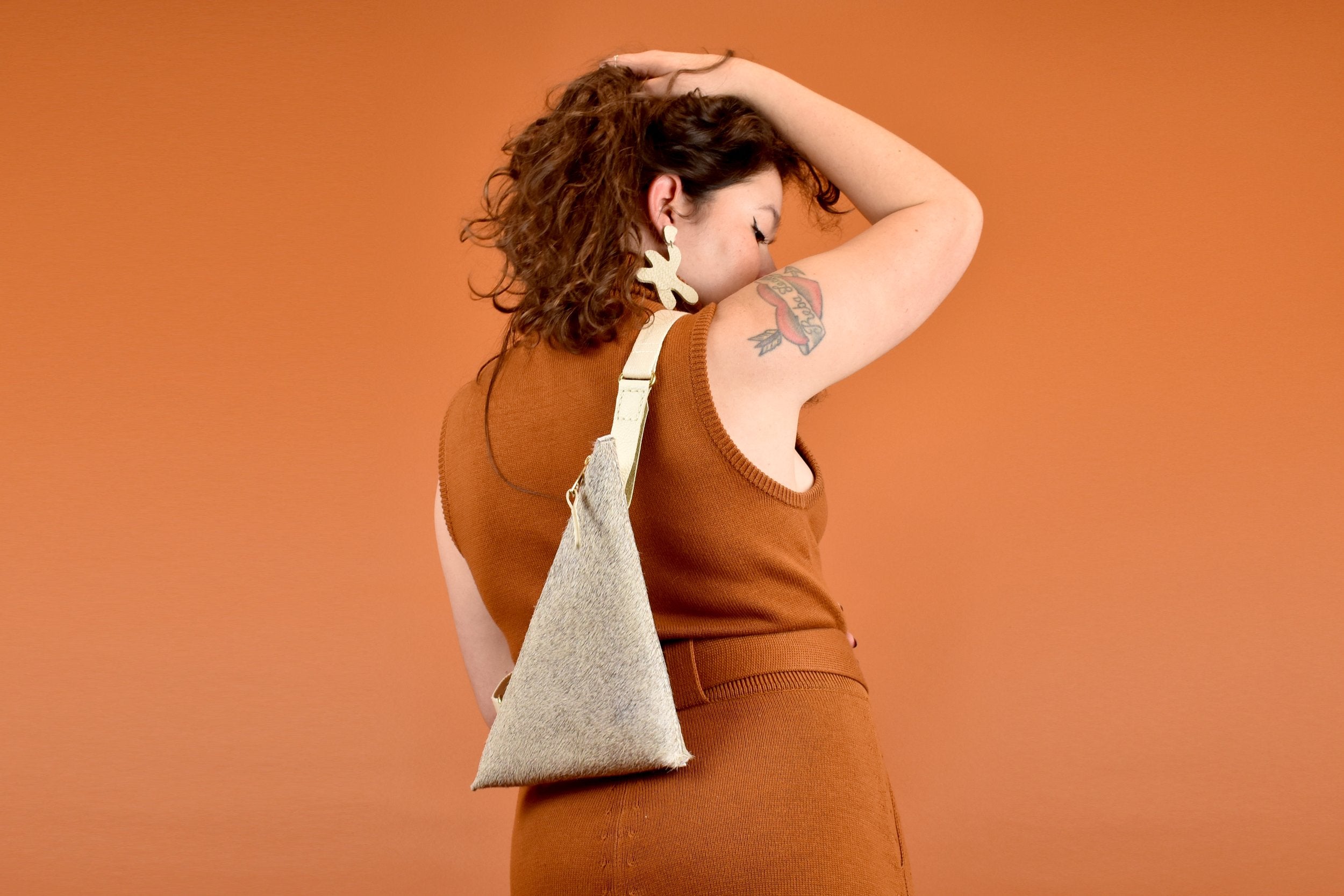 person holding hair up and wearing a leather sling crossbody bag leather clutch cute hair on hide clutch cowboy gift for maid of honor cowprint