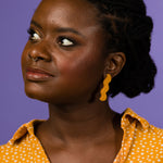 A woman wears minimal + modern lightning bolt shaped earrings in deep ochre