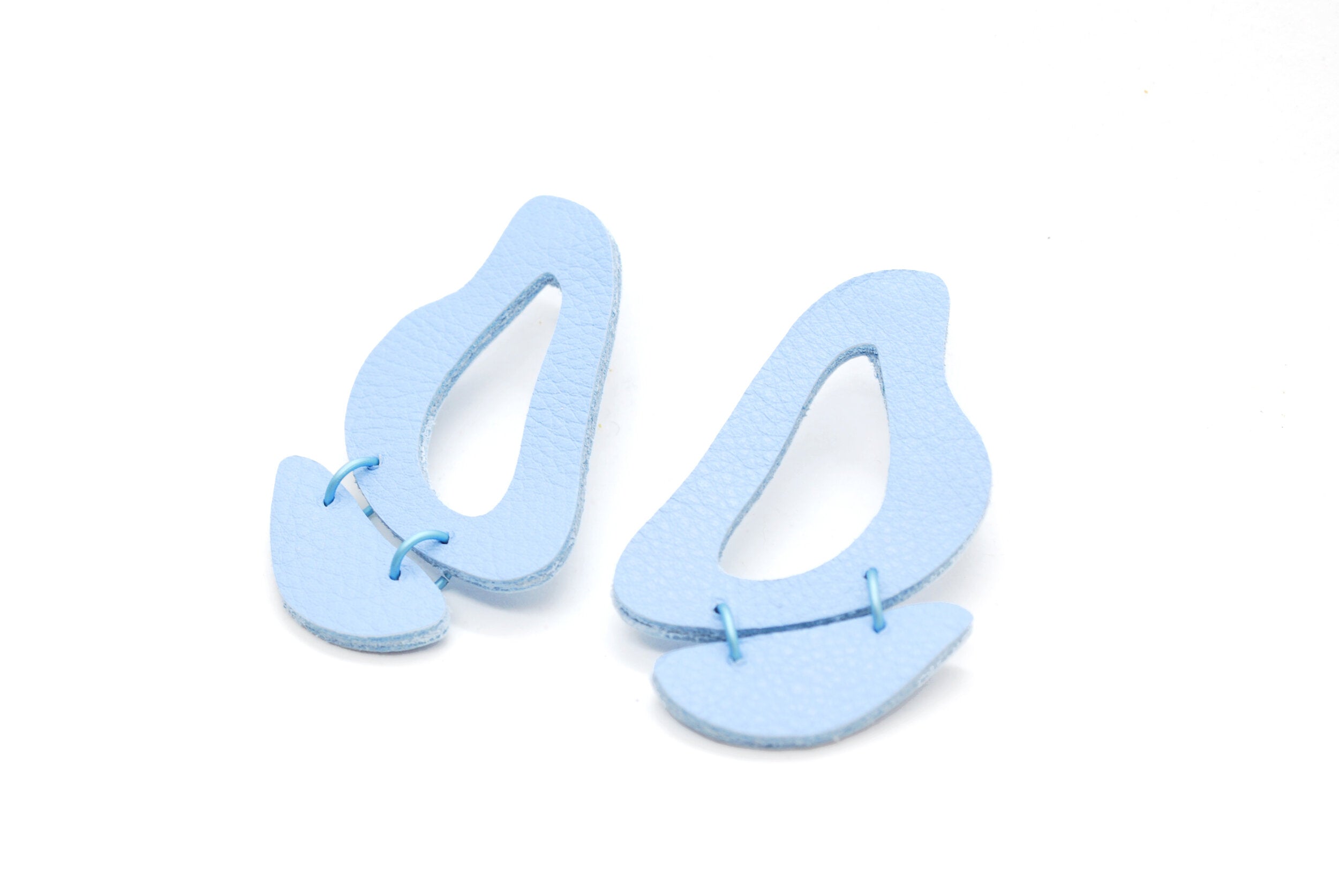 pastel blue leather earrings made of cutout organic shapes and anodized aluminum jump rings.