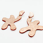 abstract statement earrings cut out leather in metallic rose finish.
