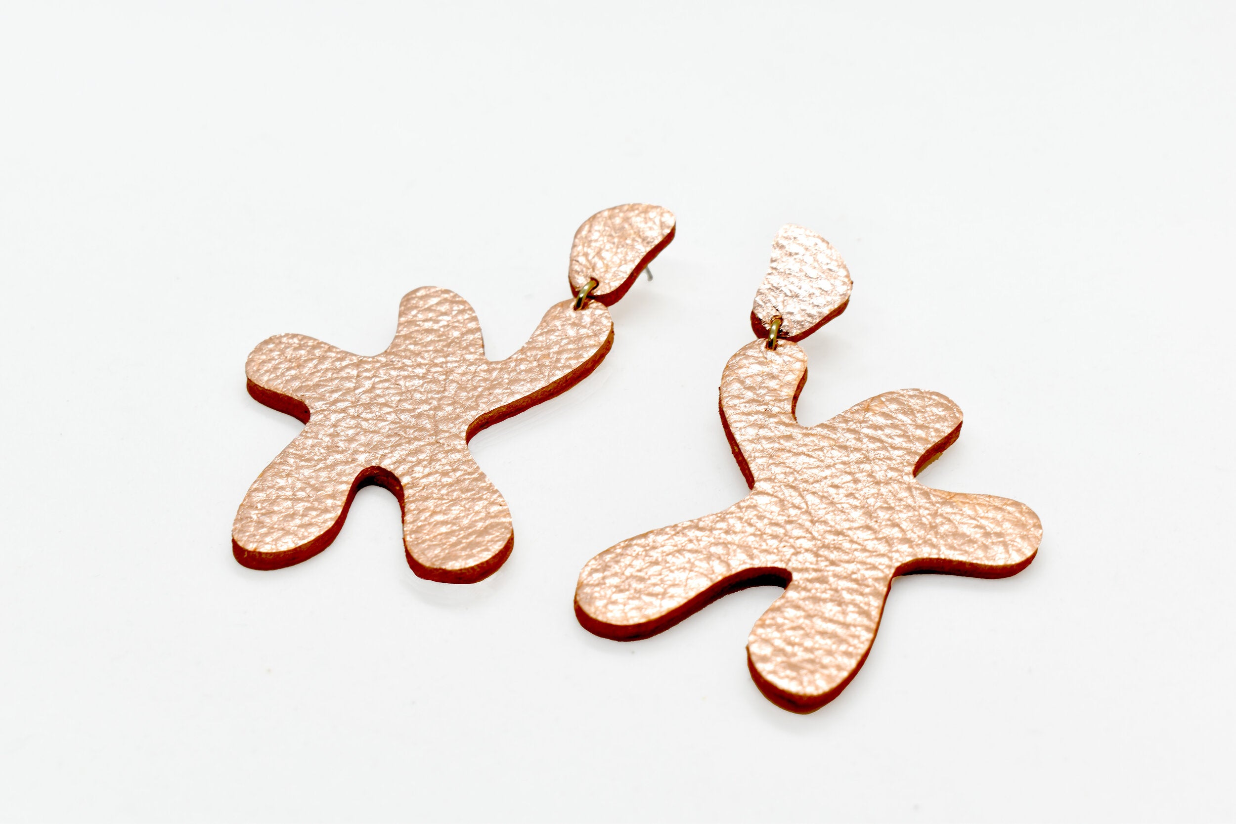 abstract statement earrings cut out leather in metallic rose finish.