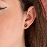 a woman wears the small delicate half moon geometric stud set in gold and ruby watercolor marble polymer clay