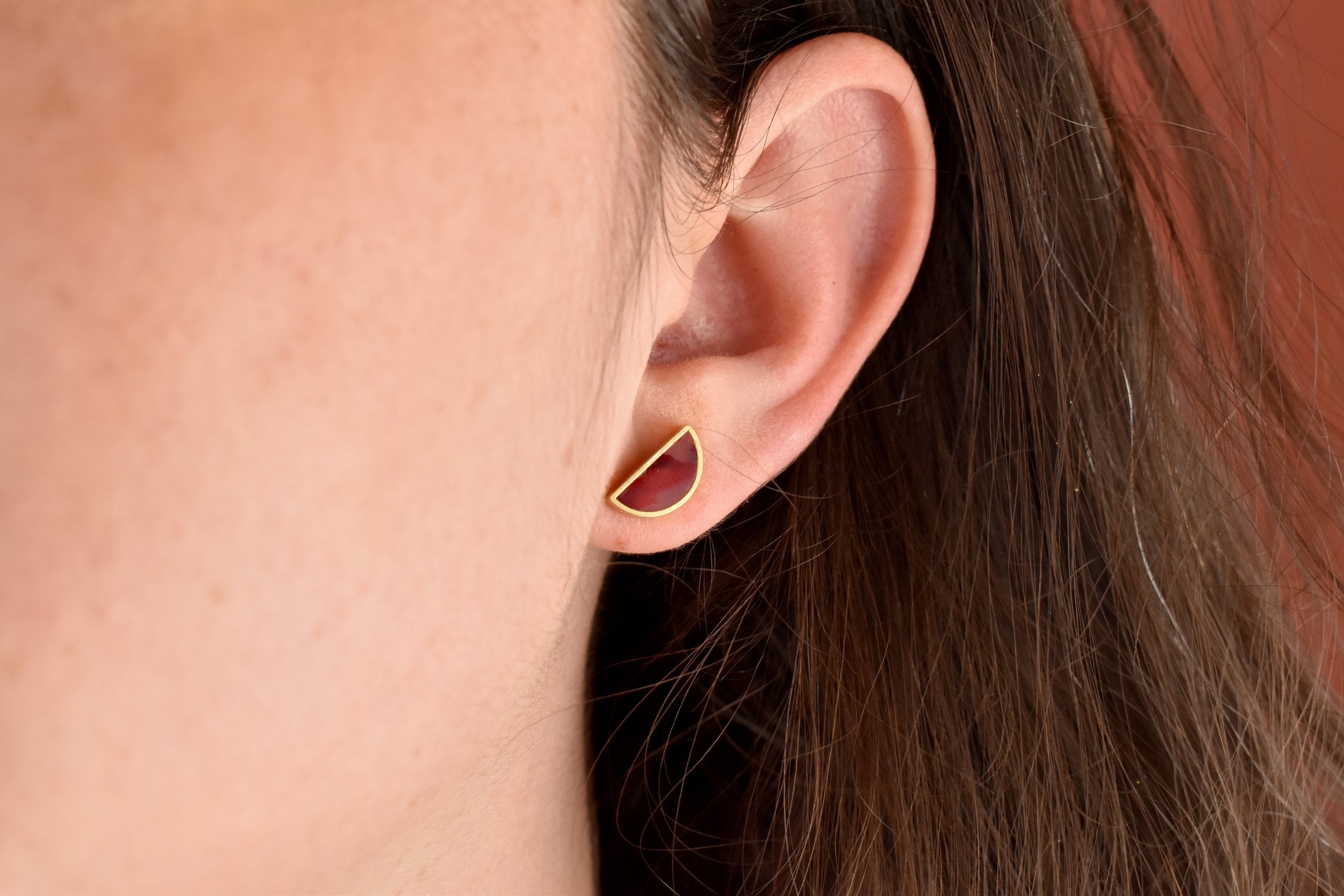 model wearing deep ruby red marbled tiny half moon earrings with 24k gold plating